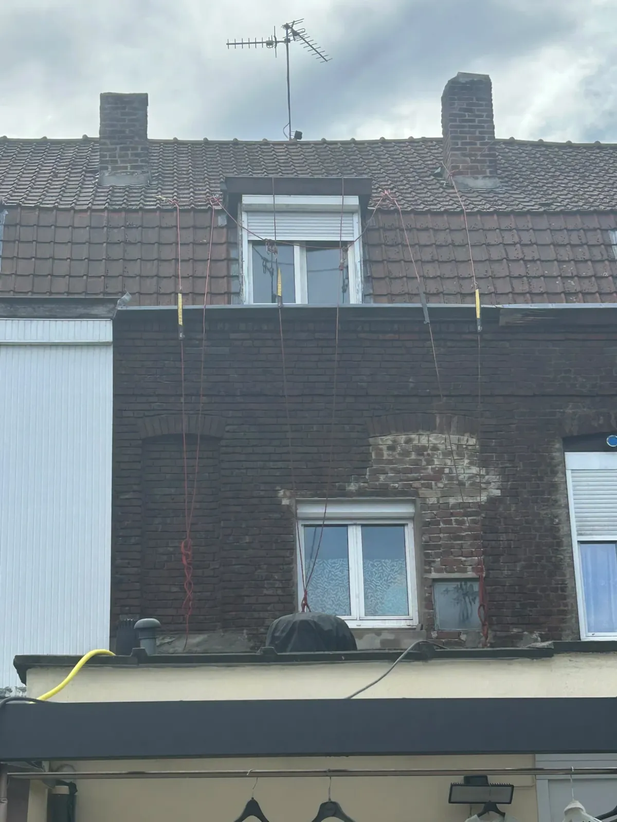 Façade en briques sombres, cordes d'accès installées depuis le toit