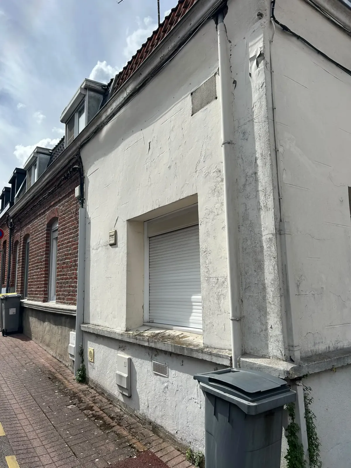 Façade blanche écaillée et fissurée avant travaux