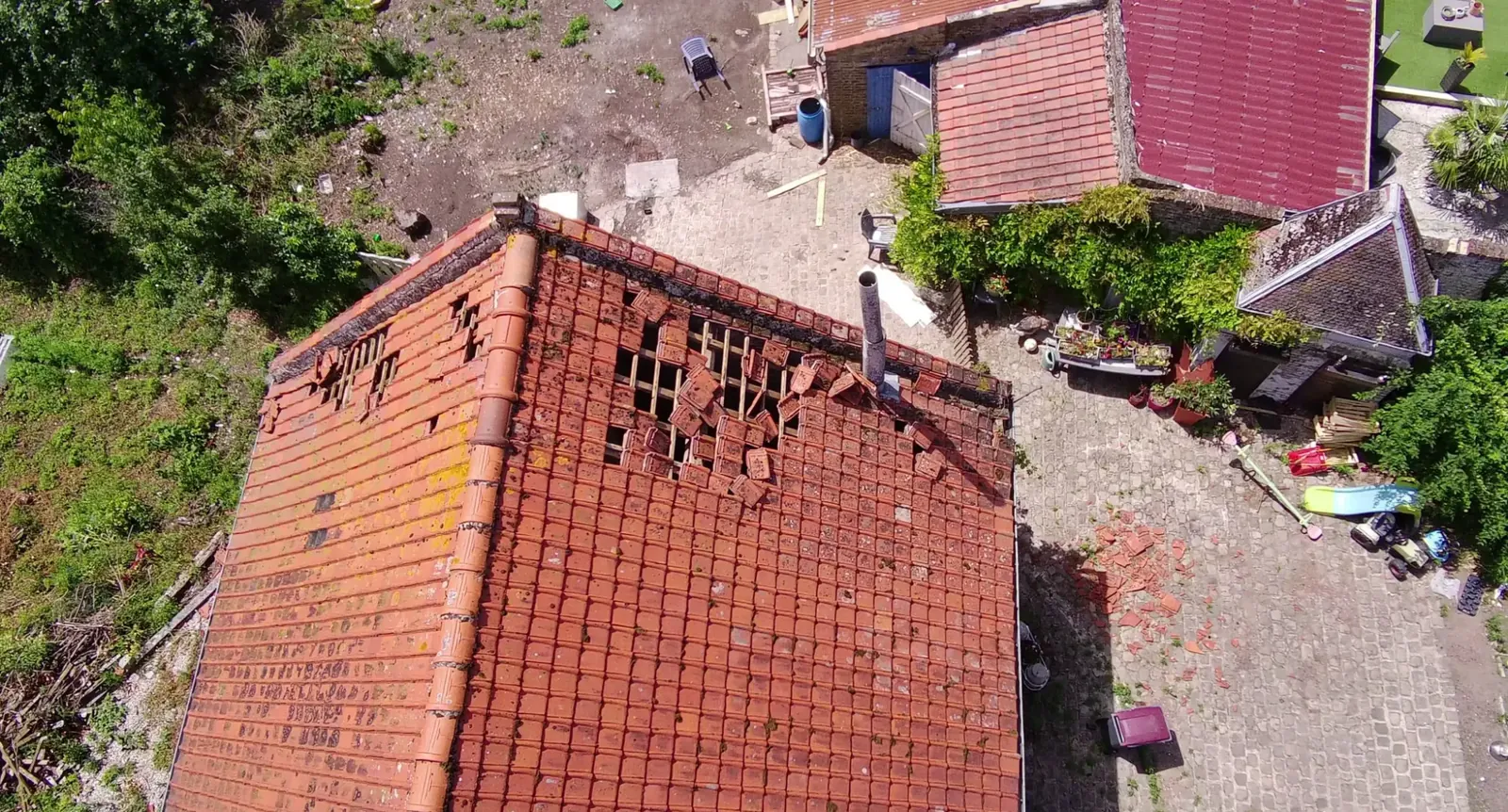 Vue de drone d'une toiture avec de nombreuses tuiles arrachées